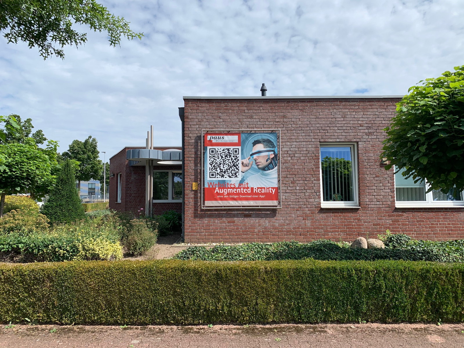 Klinkerfassade der Agentur mit einem Plakat für Websites mit Augmented Reality und QR-Code