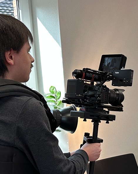 Videograf der Agentur filmt mit einer Kamera am Schwebestativ in einem Büro