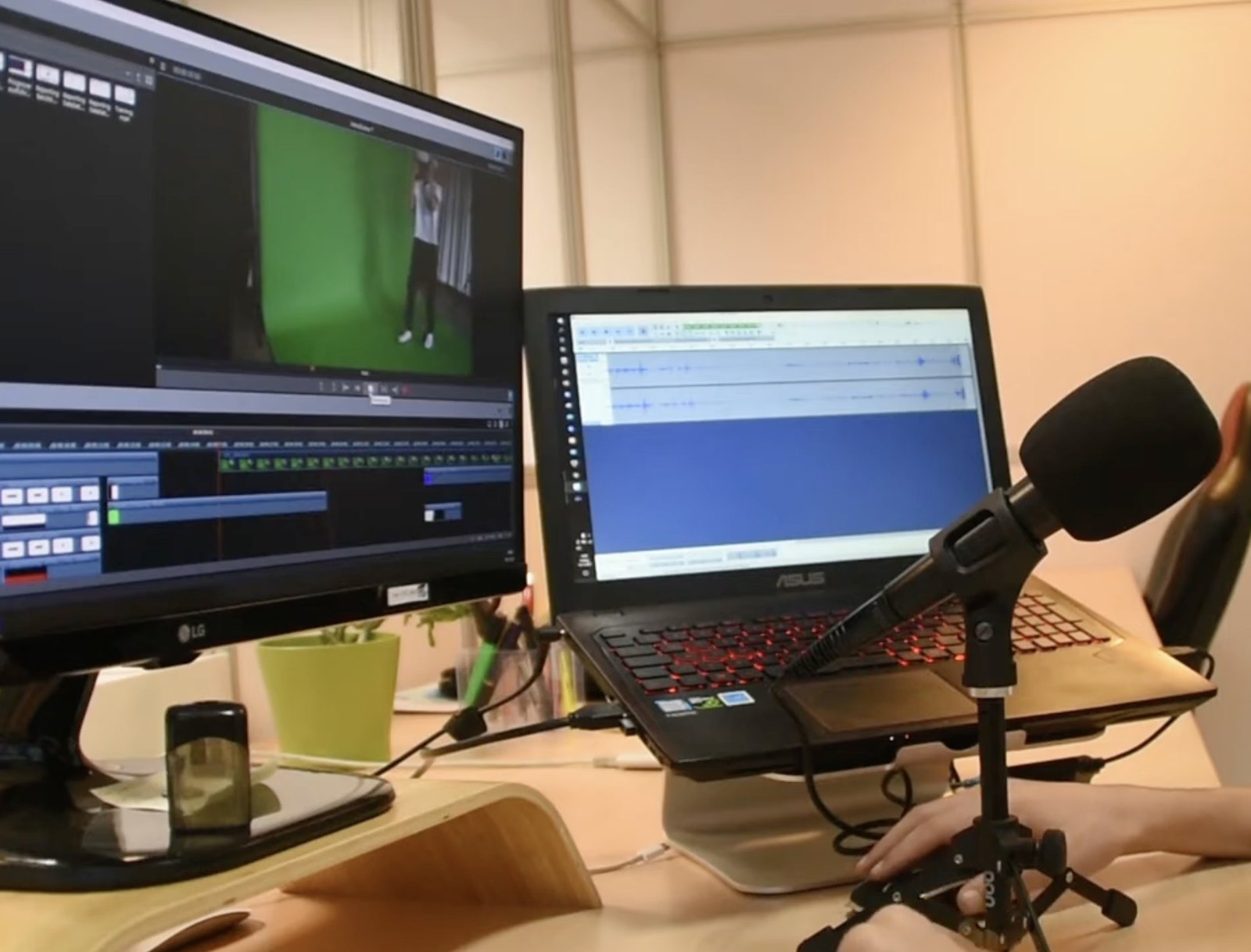 Videoschnitt in der Agentur: Auf dem Monitor läuft das Schnittprogramm mit einer Greenscreen-Aufnahme, daneben ein Laptop mit der Tonspur und ein Mikrofon