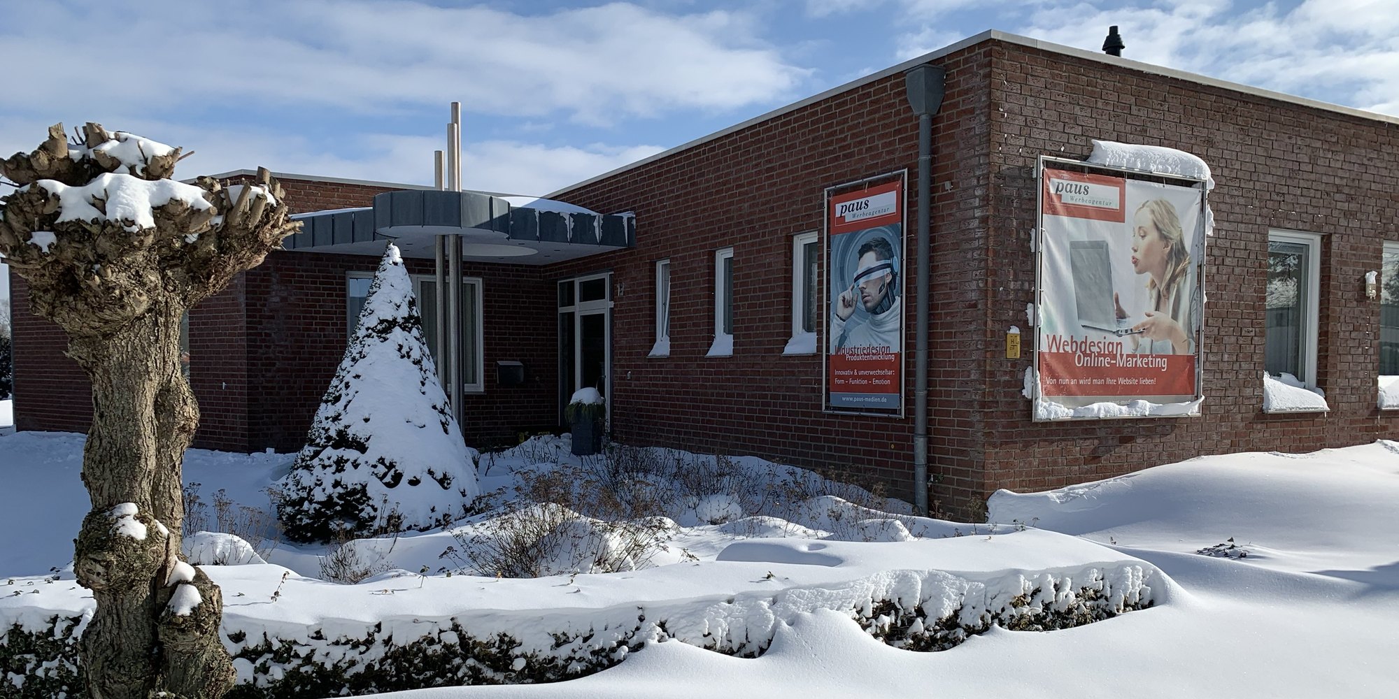 Das Agenturgebäude von Paus Design und Medien im Schnee, mit verschneitem Garten und blauem Himmel