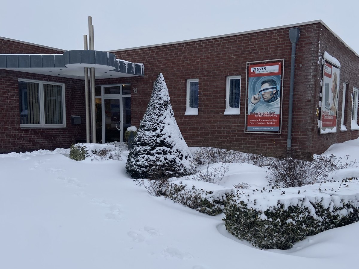 Eingang der Agentur im Schnee mit verschneitem Kegelbaum und Plakat