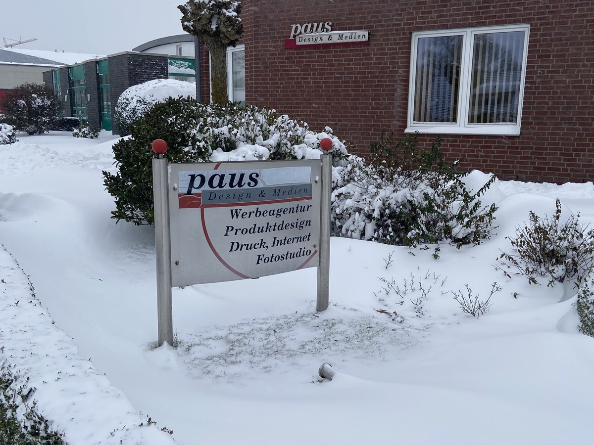 Schild der Agentur Paus Design und Medien im Schnee vor dem Gebäude