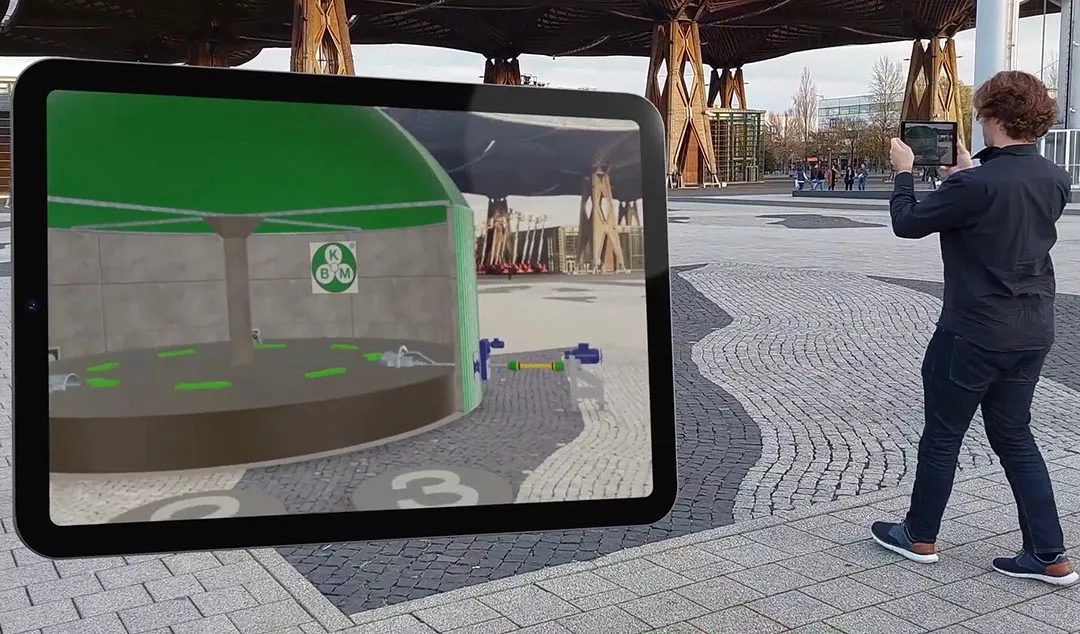 Kolja Paus hält auf einem gepflasterten Platz in Hannover ein Tablet, das ein Modell von Buschmann Maschinenbau in AR zeigt